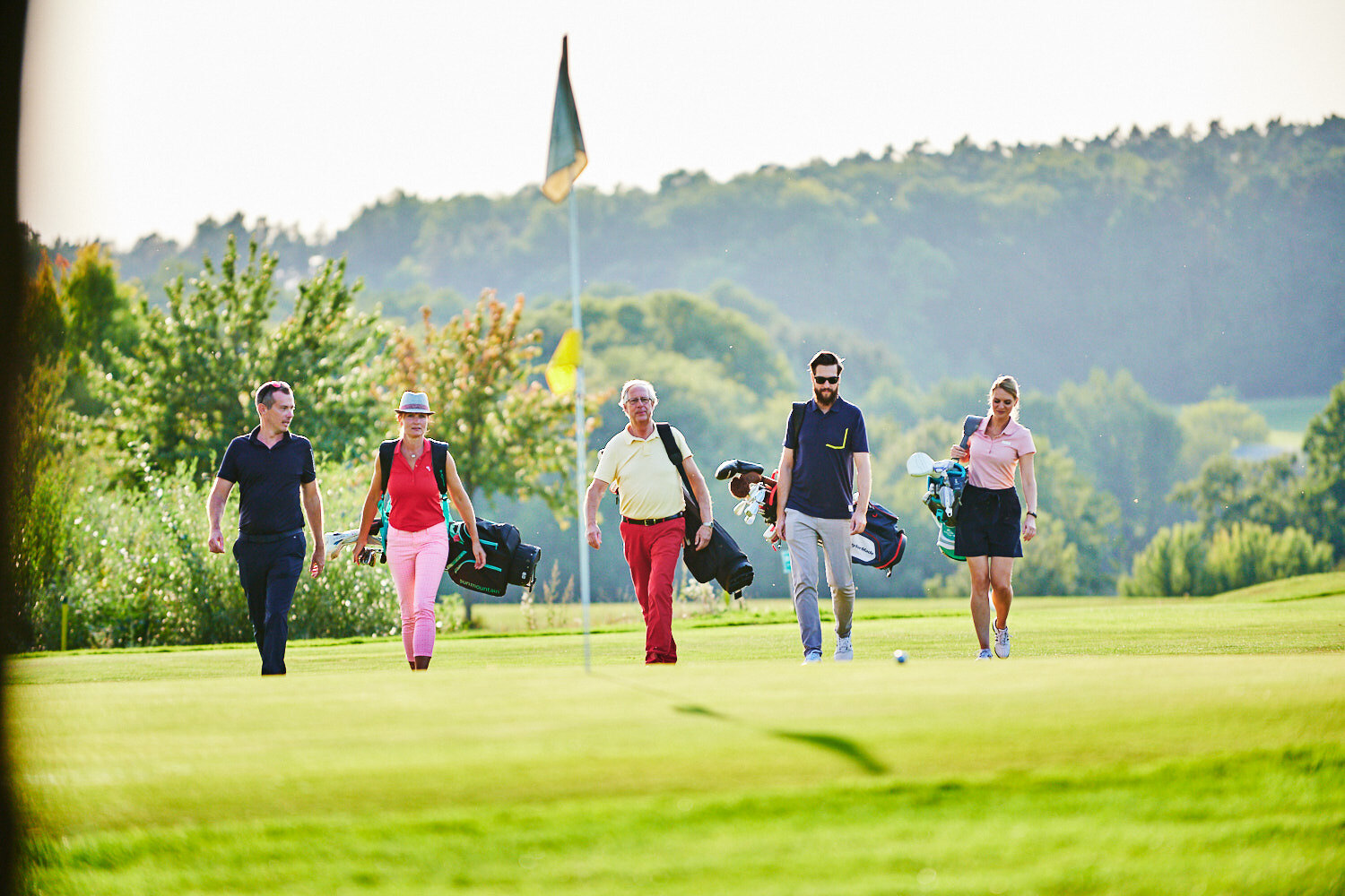 Eine Gruppe von Golferinnen und Golfern geht gemeinsam über den Golfplatz.